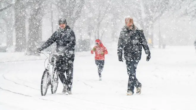 Tres personas caminan en la nieve en Nueva York