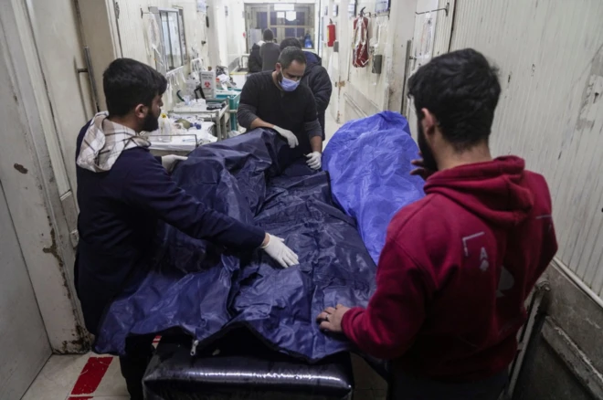 Halep'te sağlık görevlileri bir kişinin naaşını hastanede ceset torbasına koyuyor.