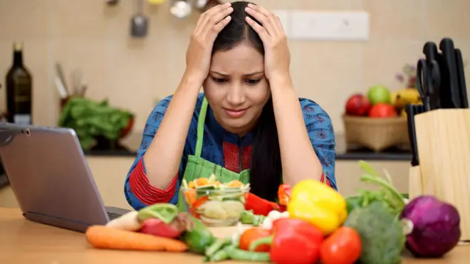 కూరగాయల దగ్గర కూర్చున్న మహిళ