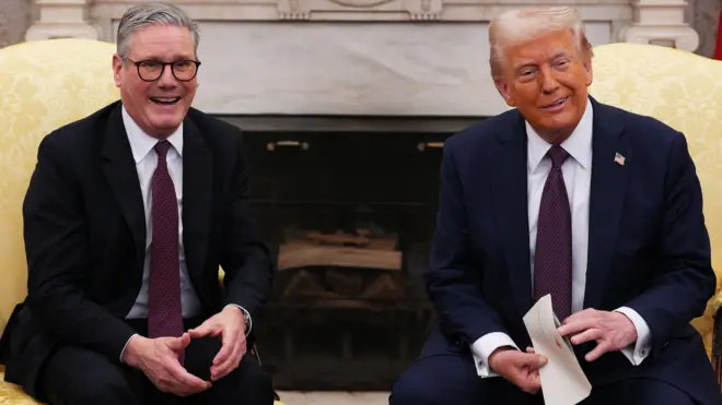 Кир Стармер и Дональд Трамп улыбаются, сидя в креслах у камина. Трамп держит в руках конверт