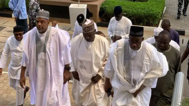 Men in white Agbada Dey climb di steps of di federal high court, Abuja