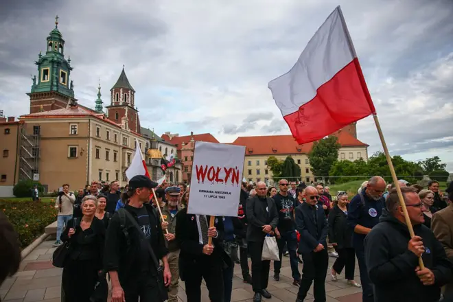Люди йдуть з прапорами Польщі, на транспаранті на передньому плані написано "Wołyń", літери написані червоним, і з них стікає кров