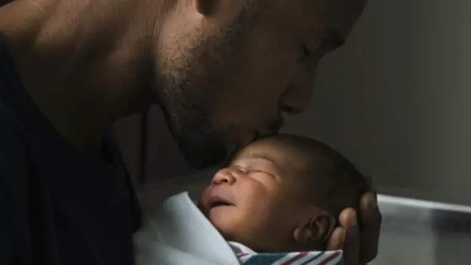 Umugabo uteruye umwana w'uruhinja