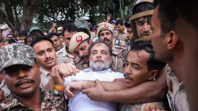 राहुल गांधी को पीएम आवास के बाहर से हिरासत में लेते पुलिसकर्मी