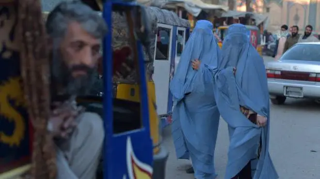 تصویر دو زن چادری پوش در شهر هرات . در مقابل آن ها یک ریکشا یا سه‌چرخه ایستاده است. 