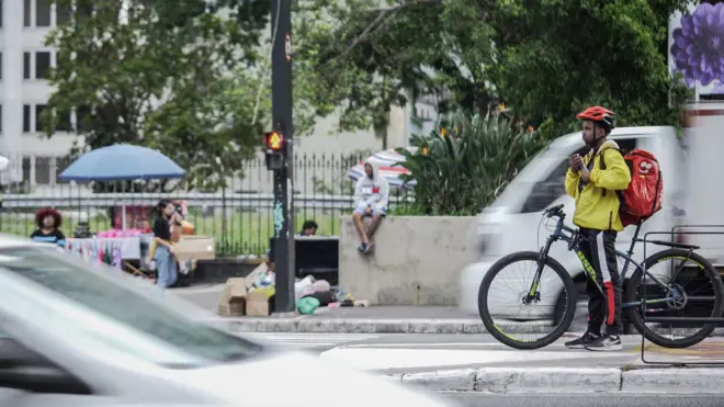 Entregador espera semáforo em ciclovia na Avenida Paulista