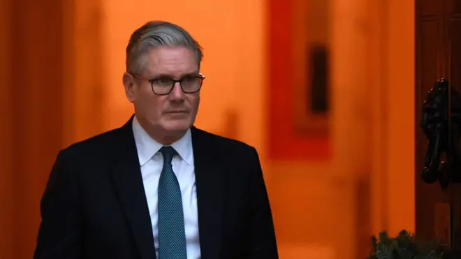 İngiltere Başbakanı Keir Starmer bir kapıdan dışarı çıkıyor.