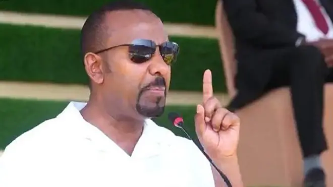 ቀዳማይ ምኒስተር ኣቢይ ኣሕመድ መደረ እናስምዐ። መነጽር ወድዩ ኢዱ ሓፍ ኣቢሉ ይርአ።