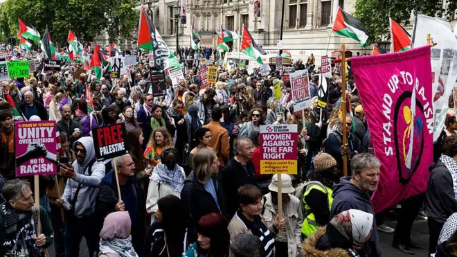 At least 100 people are seen in a picture from a portion of the Nakba Anniversary march in London - about a dozen Palestinian flags can be seen in the background, as well as placards in the foreground that say things like 'Free Palestine' and 'Unity over division'