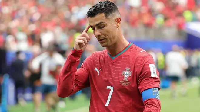 পর্তুগালের লাল জার্সি পরা ক্রিস্টিয়ানো রোনালদো নিচের দিকে তাকিয়ে আছেন এবং তার ডান হাতের একটি আঙুল চোখের কাছে কপালে ঠেকানো 