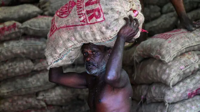 A labourer carries a sack of onions at a market in Colombo on March 20, 2023