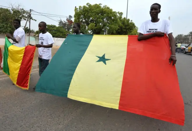 Manifestants tenant les drapeaux du Mali et du Sénégal