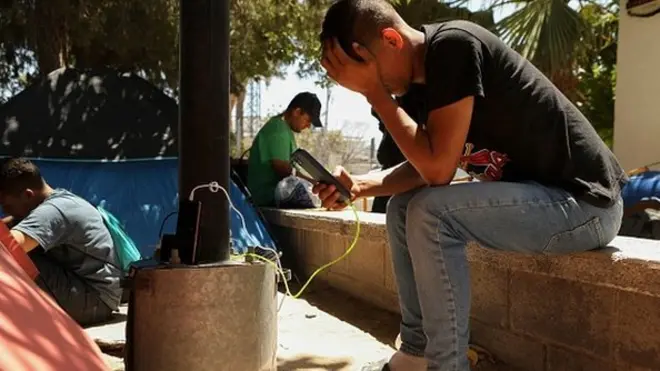 مهاجر يستخدم الهاتف المحمول