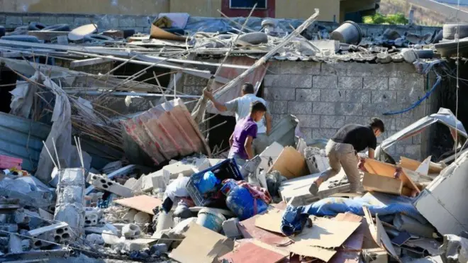 لبنانيون يبحثون عن ممتلكاتهم في مبنى متضرر بعد الغارات الإسرائيلية على جنوب لبنان في 23 سبتمبر/أيلول، في قرية قرب صيدا، جنوب لبنان، 24 سبتمبر/أيلول 2024- الصورة التقطت نهاراً.