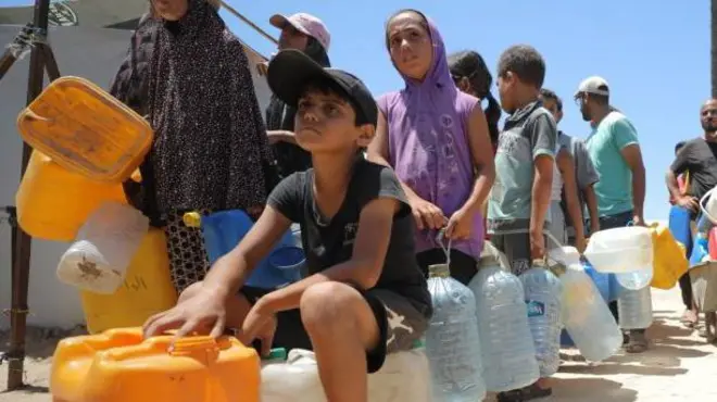Un grupo de personas con garrafas hace cola para conseguir agua.