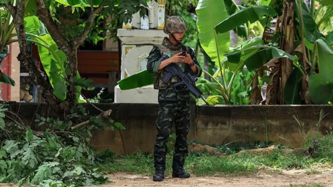 Seorang tentara sedang berjaga dengan senapan.