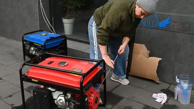 जनरेटर सुरू करताना युक्रेनमधील एक महिला 