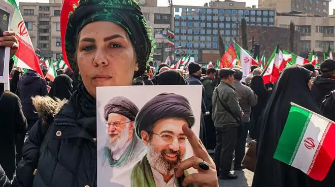 तेहरान में 9 मार्च को हुई रैली में मोजतबा ख़ामेनेई और उनके पिता आयतुल्लाह अली ख़ामेनेई की तस्वीर लिए लोग. मोजतबा को ईरान का नया सुप्रीम लीडर नियुक्त किया गया है.