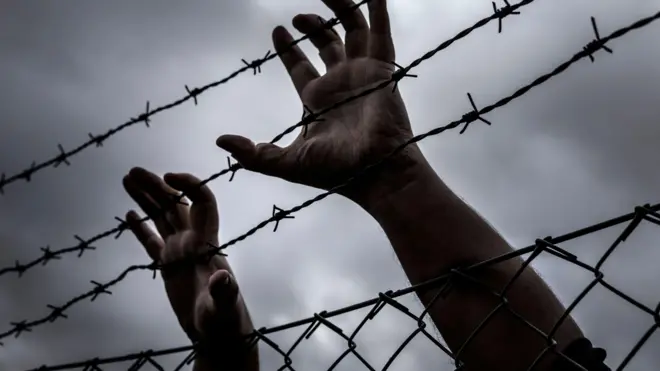 Foto wey dey show pesin hands for barbwire wey look like say e wan try to escape