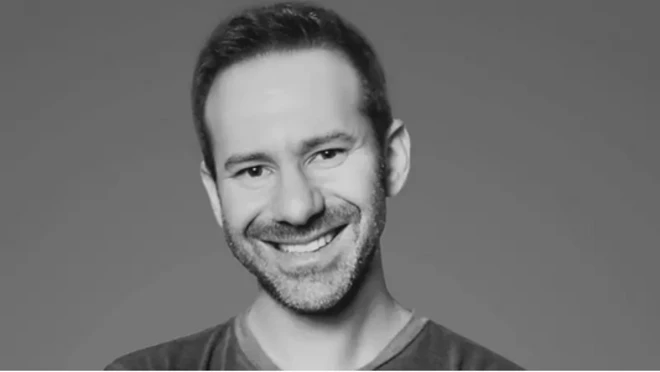 Леонид Радвинский, черно-белый портрет по грудь. Улыбающийся небритый молодой человек в футболке