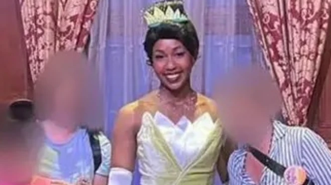 Женщина в бальном платье, рядом с другими людьми, лица которых замазаны