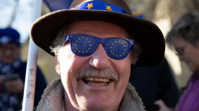 مردی با عینک پرچم اتحادیه اروپا در حال خنده 