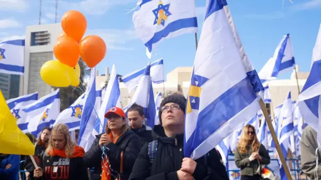 Люди с флагами Израиля и оранжевыми воздушными шарами.