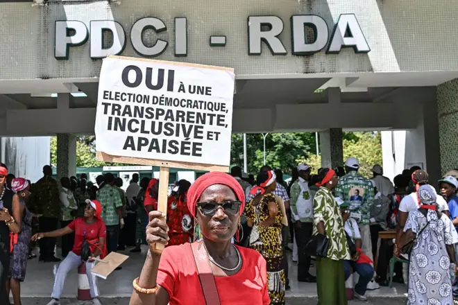 Un partisan de Tidjane Thiam, qui a démissionné de la présidence du Parti démocratique de Côte d'Ivoire (PDCI), tient une pancarte sur laquelle on peut lire « oui à une élection démocratique, transparente, inclusive et pacifique » devant le siège du parti à Abidjan, le 12 mai 2025.