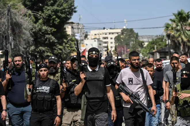 مسلحون فلسطينيون يسيرون في شوارع جنين في أعقاب غارة شنتها القوات الإسرائيلية في 23 مايو/ أيار 2024