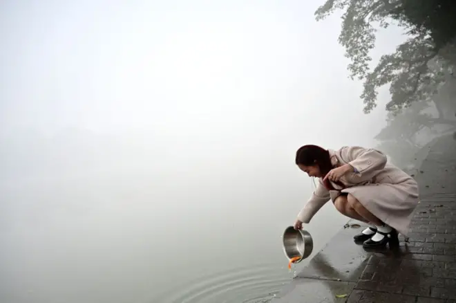 Người dân Hà Nội thả cá chép ngày 23 tháng Chạp trong bầu không khí mù mịt. Ảnh chụp sáng 2/2/2024.