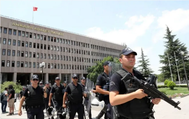 Ankara Adalet Sarayı yazılı binanın önünde eli tetikte polisleri sıra halindeymiş gibi görüyoruz.