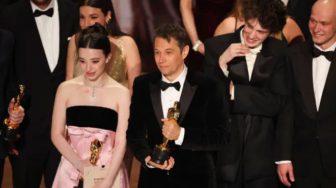 Марк Ейдельштейн, Юра Борисов і лауреат найкращої жіночої ролі Мікі Медісон стоять із режисером Шоном Бейкером на сцені після того, як "Анора" отримала нагороду за найкращий фільм під час 97-ї церемонії вручення премії "Оскар"