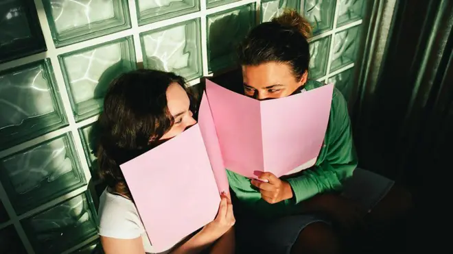 فتاتان تبتسمان خلف دفتريهما