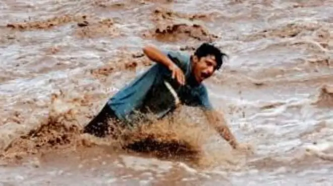 2024년 8월 4일, 파키스탄 페샤와르에서 남성이 폭우로 범람한 개울의 다리를 걸어가고 있다