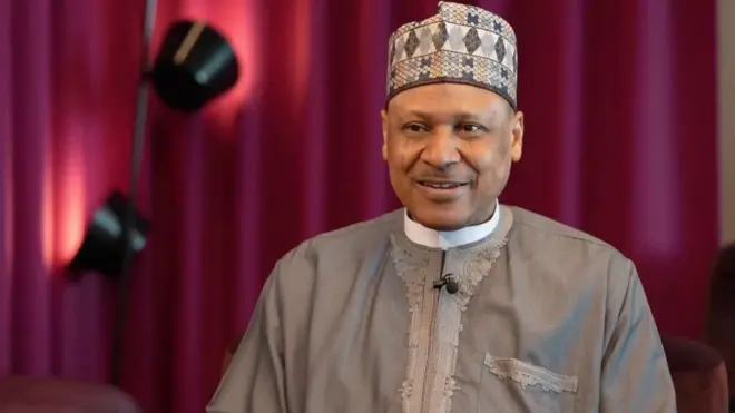 Mínísítà feto iroyin nilẹ Naijiria, Mohammed Idris Malagi wọ asọ buba ati sokoto alawọ eeru, o si de fila awọ kan naa.