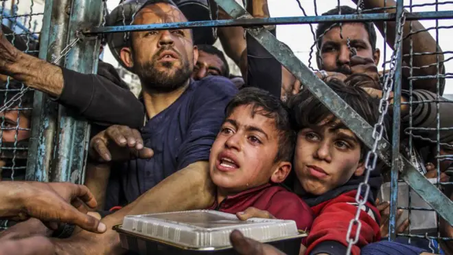 فلسطينيون يعانون من الجوع، من بينهم أطفال، ينتظرون الحصول على مواد غذائية توزعها منظمات الخيرية.