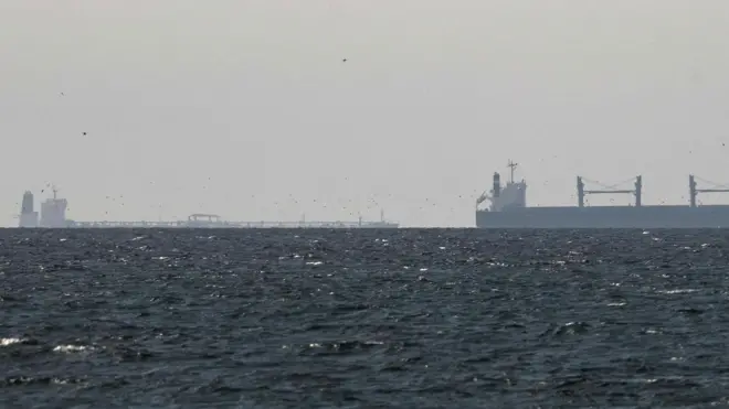 A cargo ship is seen on the horizon in the Gulf, near the Strait of Hormuz