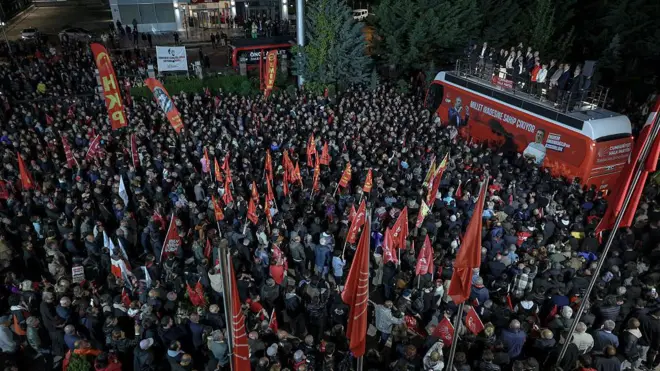 CHP otobüsünün tepesinde liderler var, yukadıdan çekilen fotoğrafta bayraklar ve geniş bir kitle görünüyor. 