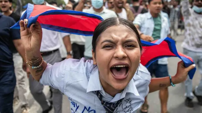 Demonstrantkinja drži nepalsku zastavu i uzvikuje slogane tokom protesta ispred parlamenta u Katmanduu 8. septembra 2025. godine, osuđujući navodnu korupciju u vladi i ograničenja na društvenim mrežama. Drži zastavu i nosi školsku uniformu sa sloganima ispisanim flomasterom