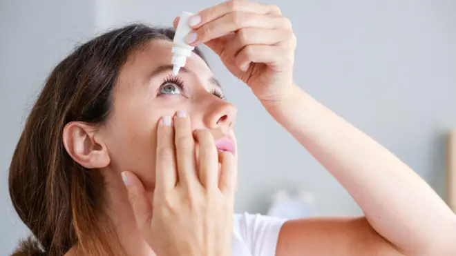 Mujer poniéndose gotas en los ojos
