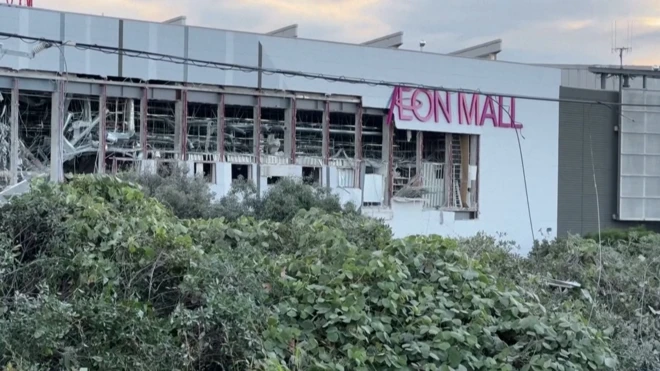 白い外壁が大きく破損して内部が見えている建物。AEON MALLとピンクの文字が壁に掲示されている