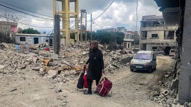 Lübnan'da bir kadın yıkıntılar arasında yürüyor. 