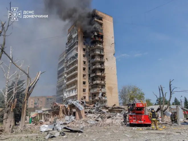 Пожежа у багатоповерховому будинку, біля нього стоїть машина 