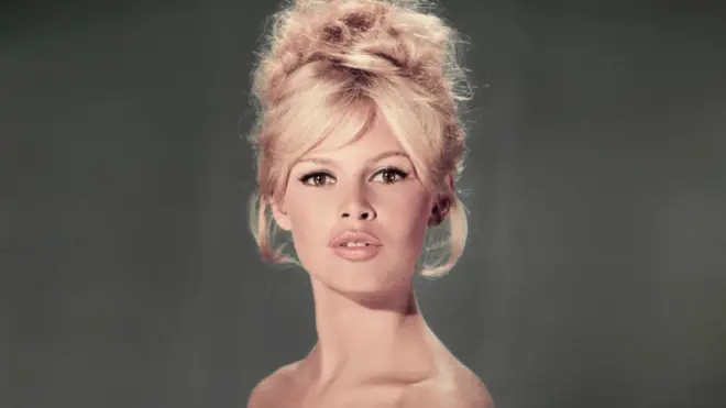 Studio portrait of actor and model Brigitte Bardot wearing a light blue off-the-shoulder dress