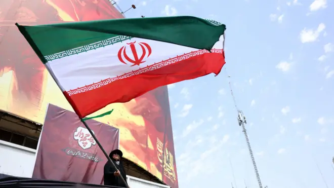 امرأة ترفع العلم الإيراني في ساحة في طهران
