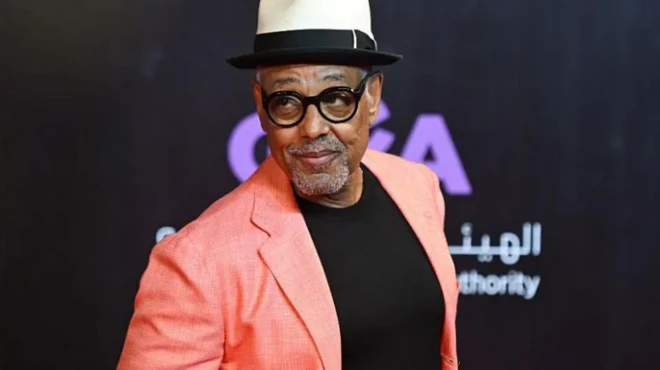 الممثل الأمريكي جيانكارلو إسبوزيتو يرتدي سترة وردية وخلفه شعار الهيئة العامة للترفيه في السعودية