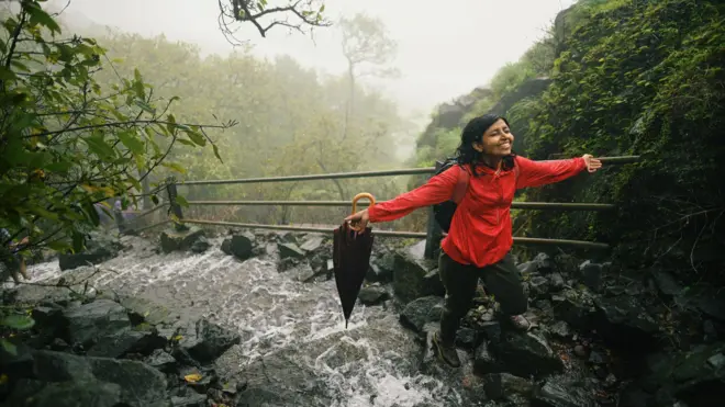 Woman enjoying during a trek standing on the steps with flowing water during monsoon 