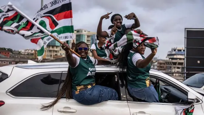 Three supporters of former president John Mahema siddon for car window and wave white, black, red and green party flags 