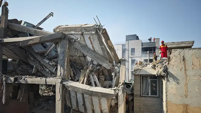 Ağır hasar almış bir bina. Üzerinde kurtarma ekipleri çalışma yürütüyor.