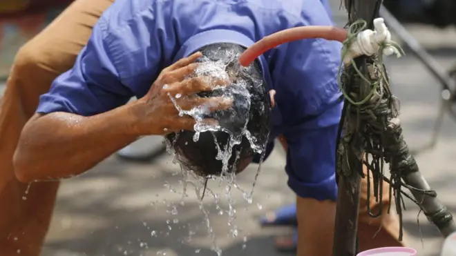 স্বস্তির খোঁজে সড়কে মাথা ধুয়ে নিচ্ছেন একজন পথচারী